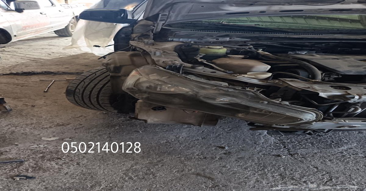عامل سمكرة يقوم بإصلاح هيكل سيارة متضرر في ورشة عمل.