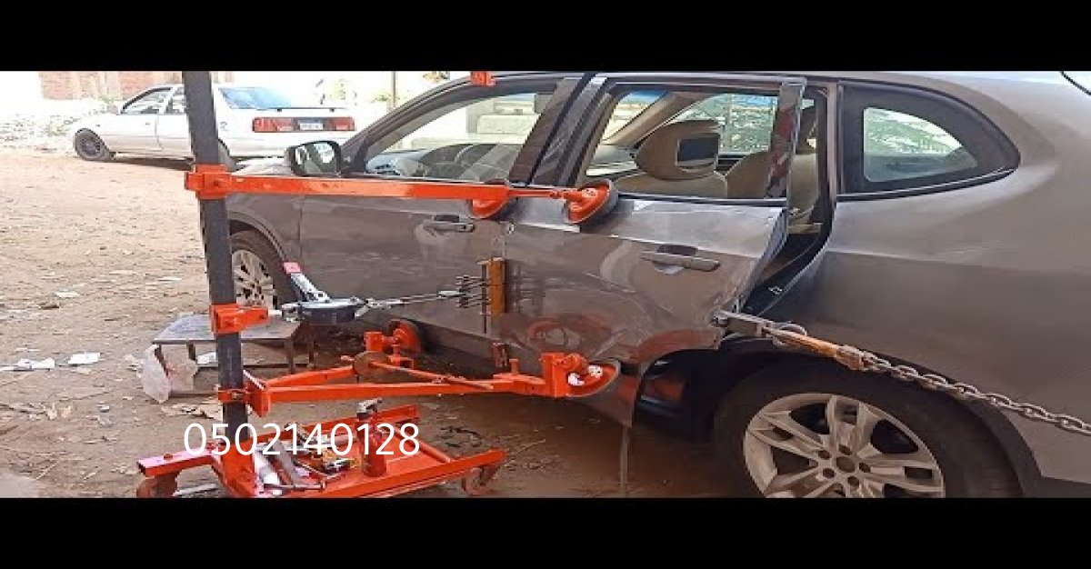 لقطة داخلية لورشة بالرياض تُظهر عملية تصليح صدمات السيارة.